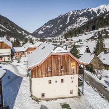 Sie sehen eine Aussenansicht vom JUFA Hotel Donnersbachwald – Almerlebnis*** aus der Vogelperspektive im Winter. Der Ort für erholsamen Familienurlaub und einen unvergesslichen Winter- und Wanderurlaub.